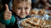 Cheerful Caucasian boy showing thumbs up while enjoying homemade pancakes with syrup and butter for breakfast, expressing happiness and satisfaction.