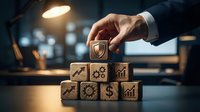 Businessman hand placing wooden block with shield icon on top of stack with business symbols in office.