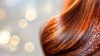 Flowing auburn hair with glitter sparkles and bokeh lights creating magical effect against soft blurred background, beauty and fashion concept.