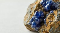 Blue sapphire crystals embedded in natural rock matrix specimen showing raw gemstone formation and geological mineral structure for collectors.