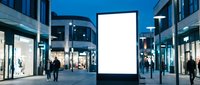 Blank white digital billboard display screen in modern shopping center plaza at evening with pedestrians walking by for advertising mockup.