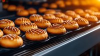 Fresh baked golden bread rolls cooling on wire racks in commercial bakery kitchen. Artisan baking process for restaurants and food service industry.