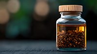 Glass jar with wooden lid containing loose black tea leaves in warm lighting against dark background with soft bokeh effect. Perfect for tea packaging and marketing.