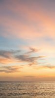 Dramatic sunset sky with swirling clouds in shades of pink, orange, and gold above calm ocean waters, ideal for travel and nature backgrounds.