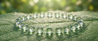 Elegant crystal bead bracelet with transparent spheres on green textured surface with soft natural lighting and bokeh background for jewelry design.