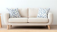 Modern beige loveseat sofa with blue polka dot throw pillows on wooden legs against white wall, minimalist Scandinavian living room furniture design.