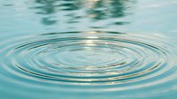 Concentric water ripples spreading across calm turquoise surface creating peaceful zen meditation atmosphere for wellness and relaxation concepts.