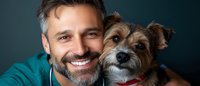 Happy middle-aged Caucasian man with beard smiling while holding small Yorkshire Terrier dog. Portrait of pet owner and companion animal bonding moment.