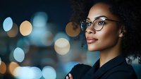 Professional African American businesswoman with glasses and curly hair against blurred city lights bokeh background for corporate presentations and marketing.