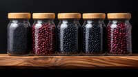 Glass jars filled with black and red beans arranged in row on rustic wooden shelf against dark background, showcasing natural food ingredients and storage.