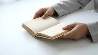 Professional hands in white shirt turning pages of open book on clean white surface for business education and learning concepts.
