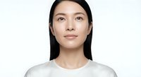 Young Asian woman with long black hair wearing white t-shirt looking up with hopeful expression against light background for lifestyle and wellness concepts.