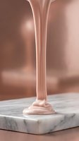 Smooth pink liquid foundation stream flowing onto marble surface creating elegant puddle for cosmetic beauty product advertising and makeup industry.