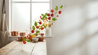 Fresh vegetables and herbs flying from copper bowl on wooden table near bright window creating dynamic culinary motion in modern kitchen interior.