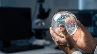 Scientist holding transparent globe with digital earth map in laboratory environment, representing global technology, research, and innovation.