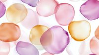Translucent glass spheres in soft pink, purple, and golden tones scattered on white background, suitable for abstract backgrounds and design projects.