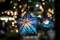 Blue glittery star ornament hanging with warm bokeh lights in background creating festive holiday atmosphere for seasonal decorations and celebrations.