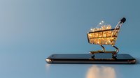Shopping cart filled with glowing golden coins on smartphone screen against blue background, representing mobile commerce and digital payment solutions.