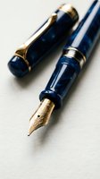 Luxury fountain pens with deep blue barrels and gold-tone metal accents arranged on white surface. Writing instruments for professional correspondence and calligraphy.