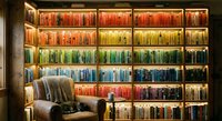 Cozy reading nook with illuminated rainbow bookshelf displaying colorful book collection in warm library interior for home decor and literary themes.