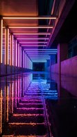 Modern architectural corridor with vibrant neon lighting creating purple and orange gradient reflections on wet pavement for futuristic design concepts.