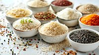 Various types of rice, grains, and spices in white ceramic bowls arranged on light surface, perfect for food blog, restaurant menu, or cooking website design.