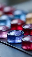 Shimmering makeup eyeshadow palette with metallic blue and red pigments in close-up view, showing luxurious cosmetic texture and sparkle effect for beauty industry.