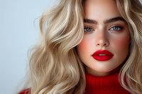 Young woman with blonde wavy hair, bright red lipstick and natural makeup wearing red turtleneck sweater against light background, fashion beauty portrait.