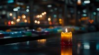 Glowing orange candle with melting wax against dark blurred background with bokeh lights creates atmospheric mood for spiritual or romantic concepts.