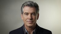 Middle-aged man with gray hair and light complexion wearing dark jacket over checkered shirt, neutral expression against gray background for corporate or professional use.