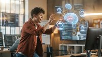 Young male professional with curly dark hair, wearing a rust-colored shirt, interacting with holographic artificial intelligence interface displaying brain and tech icons in modern office environment for technology and innovation concepts.