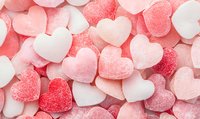 Pink and white sugar coated heart shaped candy background pattern. Sweet romantic confectionery texture with gummy jelly hearts in pastel colors.