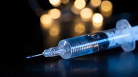 Medical syringe with needle on dark surface with warm bokeh lights background for healthcare and vaccination concepts.