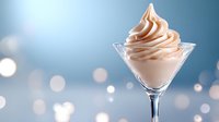 Creamy soft serve dessert swirled in martini glass against blurred bokeh background, elegant presentation with smooth texture and delicate pink hue.
