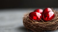 Shiny red Easter eggs nestled in natural brown twigs nest against dark background, selective focus creates soft dreamy atmosphere. Festive spring holiday concept.