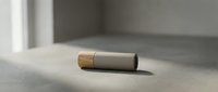 Modern minimalist cosmetic tube with wooden cap on concrete surface in natural sunlight for skincare and beauty product packaging.