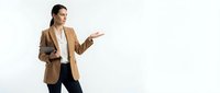 Professional businesswoman in beige blazer presenting with open palm gesture against white background for corporate marketing materials.