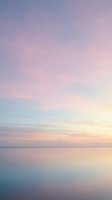 Serene dawn seascape with soft pastel sky reflecting on calm ocean waters, capturing tranquil morning atmosphere for wellness and meditation projects.