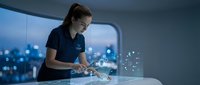 Young professional woman using futuristic holographic interface technology in modern office environment with digital data visualization and city lights.
