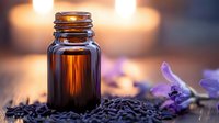 Amber glass essential oil bottle with lavender flowers and seeds on wooden surface with warm bokeh background for aromatherapy and natural wellness products.