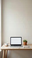 Clean minimalist workspace with open laptop, coffee cup and succulent plant on wooden desk against neutral beige wall for remote work and productivity.