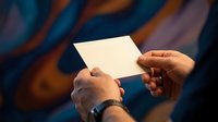 Hands holding blank white card against colorful blurred background for mockup design templates and business presentations.