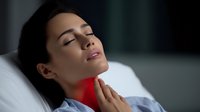 Young woman with sore throat touching neck with red inflammation indicator. Concept for throat pain, tonsillitis, or respiratory illness.