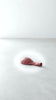 Deflated red balloon lying on white concrete floor in minimalist studio setting, symbolizing loss, disappointment, or failed expectations for conceptual design projects.