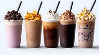 Variety of cold coffee drinks and milkshakes with whipped cream, chocolate chips, caramel drizzle and toppings in tall glasses on white background.