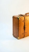 Vintage brown leather suitcase with brass corners and buckles isolated on white background for travel and retro design concepts.