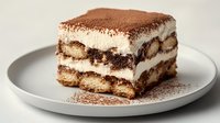 Classic tiramisu dessert slice with cocoa powder dusting on white plate, Italian coffee-flavored cake with mascarpone cream layers for restaurant menu.