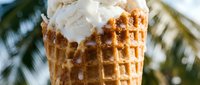 Waffle cone filled with vanilla ice cream and topped with whipped cream, perfect for summer dessert, food photography, and restaurant menus.