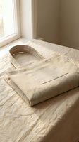 Natural linen tote bag with blank label on bed near window in soft morning light for sustainable fashion and eco-friendly shopping concepts.