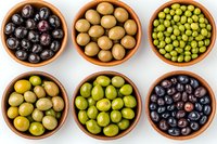 Fresh assorted olives and green peas in traditional terracotta bowls arranged in grid pattern on white background, top view of Mediterranean appetizers.